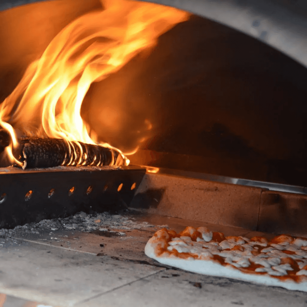 Wood fire blazing inside XO 40 Inch Countertop Outdoor Oven with pizza baking on stone surface, perfect for authentic outdoor cooking.