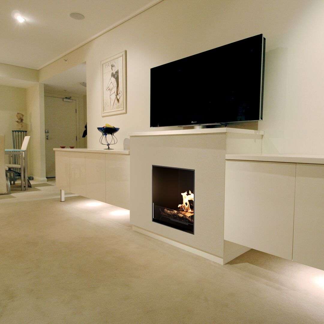 EcoSmart Heritage 26SS Ethanol Fireplace Insert - ESF.HB.26SS installed in a modern living room under a wall-mounted TV, blending with minimalist decor.