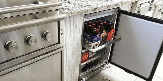 XO 15 Inch Outdoor Undercounter Refrigerator built into outdoor kitchen cabinetry, fully stocked with beverages and designed for seamless integration.