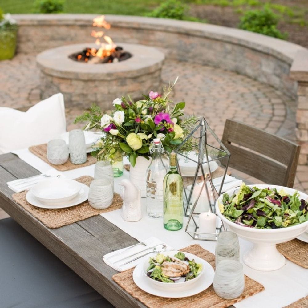 Outdoor dining scene with Firegear DIY Fire Pit Kit - Round in the background, enhancing ambiance for meals and social events.