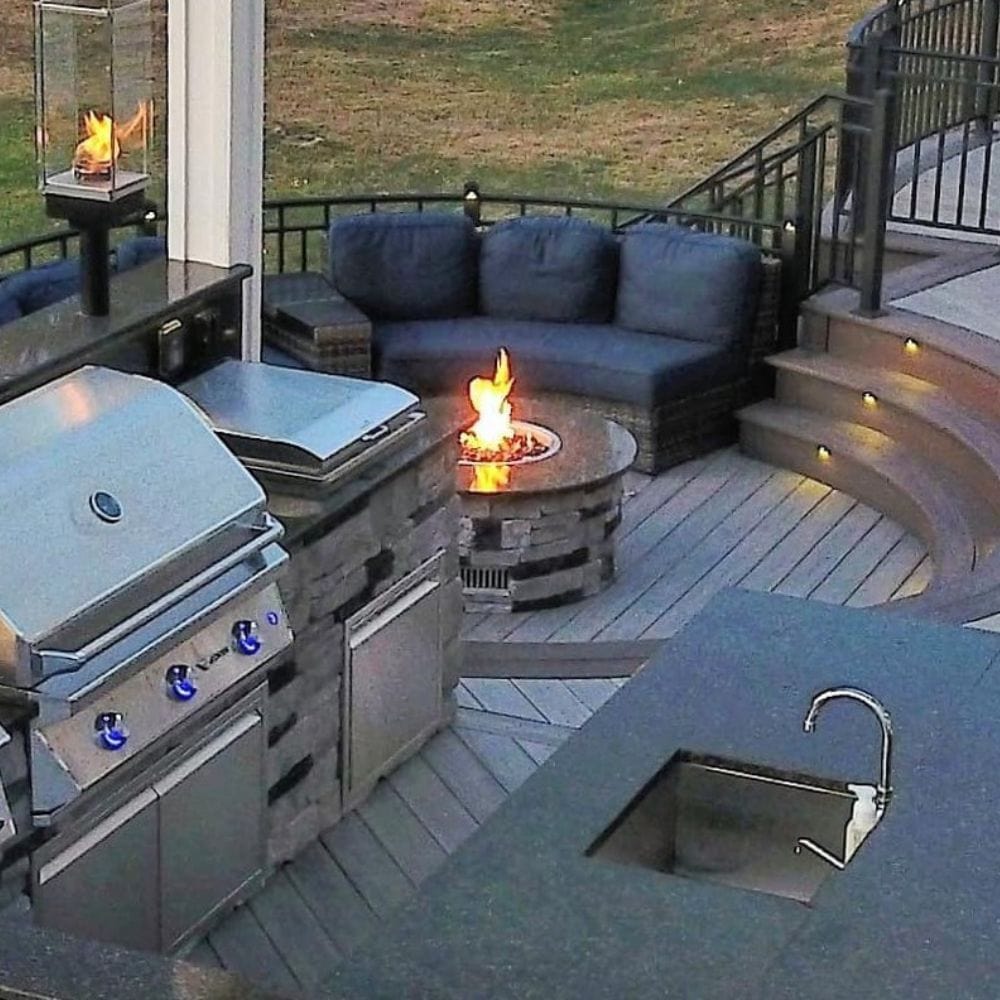 Outdoor kitchen with Firegear DIY Fire Pit Kit - Round integrated into stone table, creating a luxurious backyard experience.
