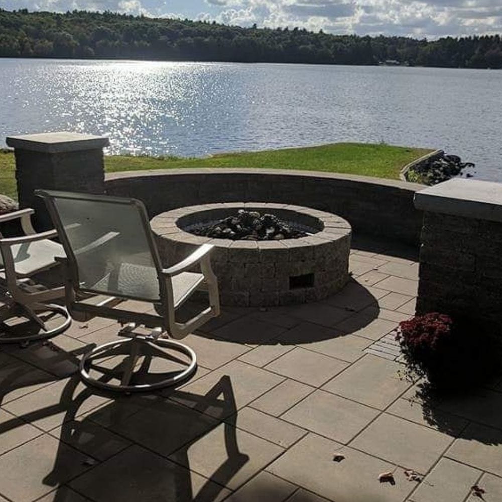 Lakeside patio with Firegear DIY Fire Pit Kit - Round installed in stone enclosure, offering scenic relaxation by the water.
