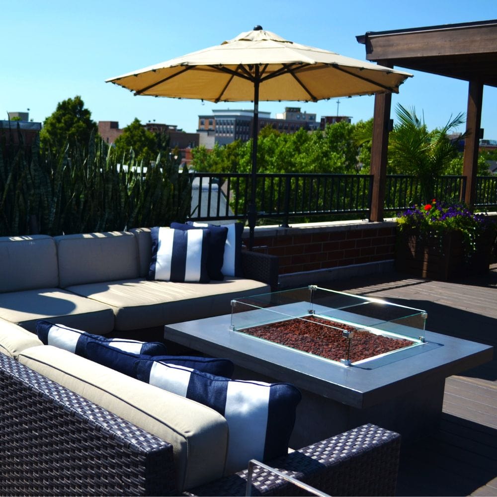 Rooftop lounge with Firegear DIY Fire Pit Kit - Square in a modern concrete base with glass wind guard and lava rocks.