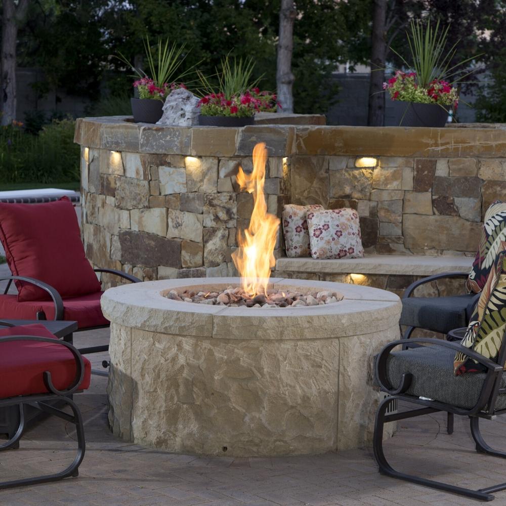 Firegear DIY Fire Pit Kit - Round installed in a stone fire pit with high flame, surrounded by cushioned patio chairs.