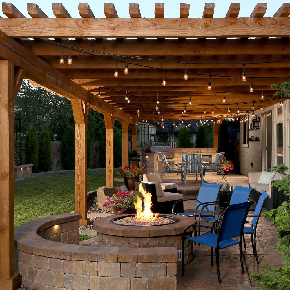 Covered patio with Firegear DIY Fire Pit Kit - Round as centerpiece, surrounded by string lights and modern outdoor seating.