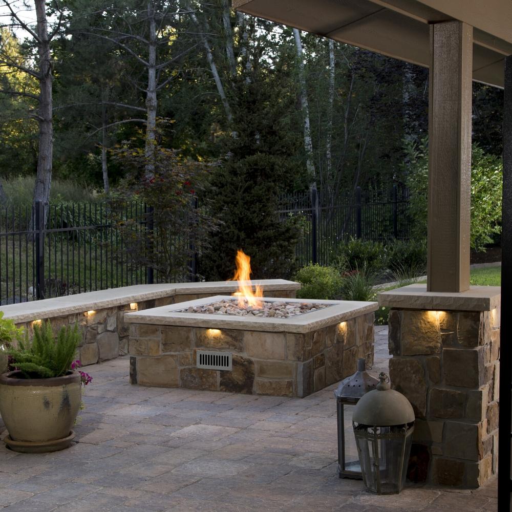 Stone patio with built-in Firegear DIY Fire Pit Kit - Square surrounded by stone seating and ambient lighting for outdoor gatherings.