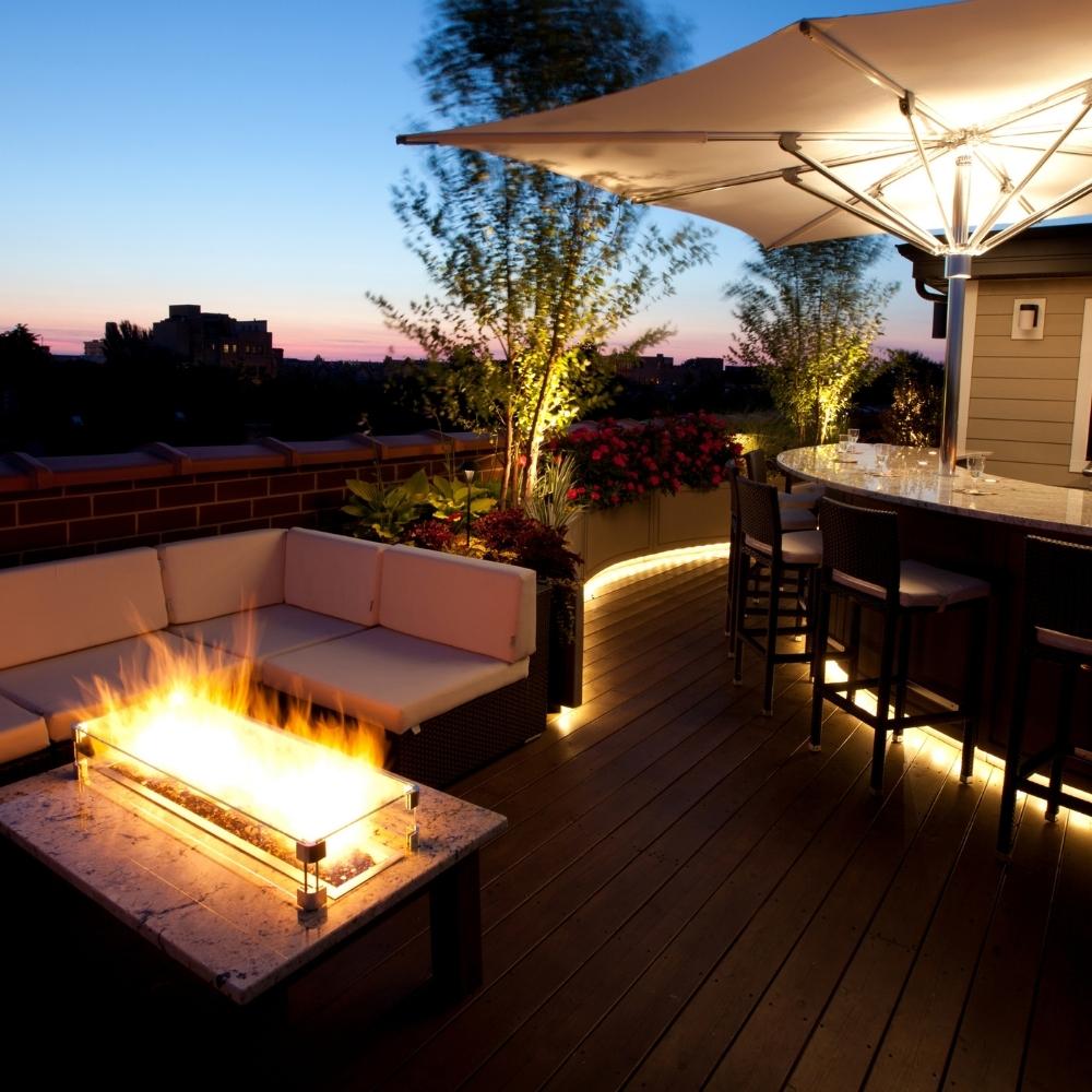 Modern rooftop patio with Firegear Pro Series H Burners - Brass Gas Burner installed in a fire table, enhancing evening outdoor gatherings.