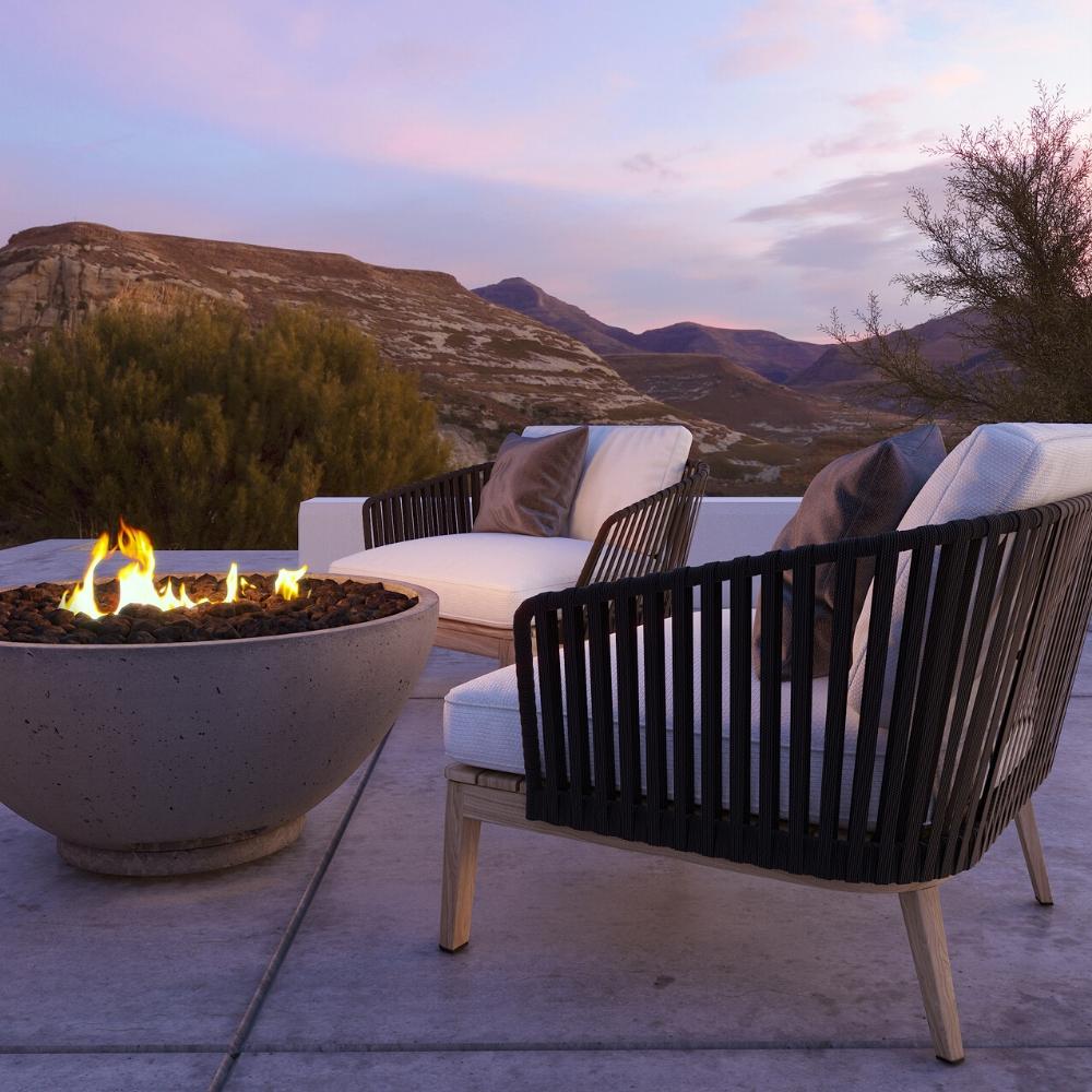 Firegear Sanctuary 39-Inch Round Concrete Gas Fire Bowl in Arctic finish with flame, set on a scenic patio with modern seating.