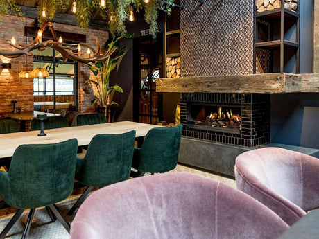 NetZero Fire E-One 130F 3D Electric Fireplace - Front - AA-11-05387 installed in a chic dining space with velvet chairs, wood accents, and lush greenery.