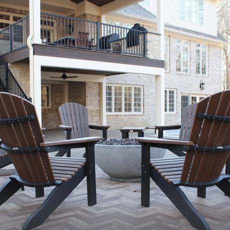 Backyard patio with Adirondack chairs surrounding Firegear Sanctuary 30-Inch Round Concrete Gas Fire Bowl for outdoor gatherings.