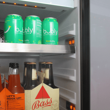 XO 15 Inch Outdoor Undercounter Refrigerator stocked with Bubly sparkling water and Bass beer, showing adjustable shelving and LED lighting.
