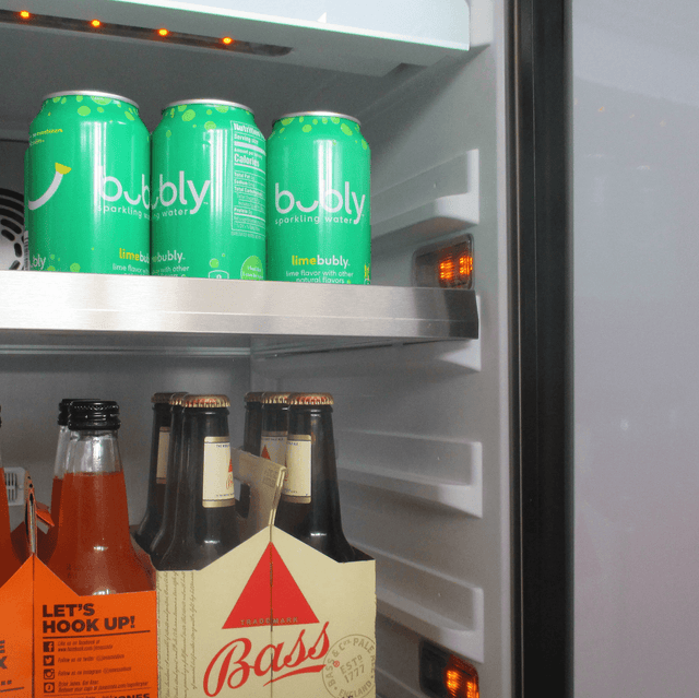 XO 15 Inch Outdoor Undercounter Refrigerator stocked with Bubly sparkling water and Bass beer, showing adjustable shelving and LED lighting.